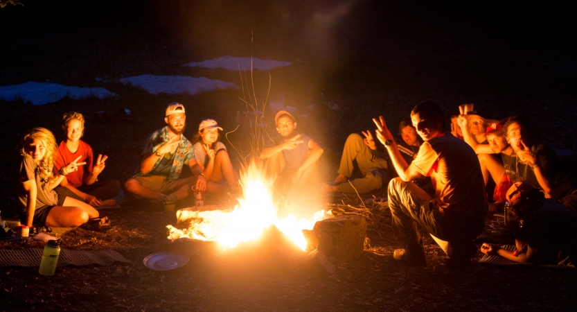 A group of people sit around a campfire. 